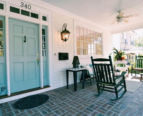 front porch with teal door and rocking chairs